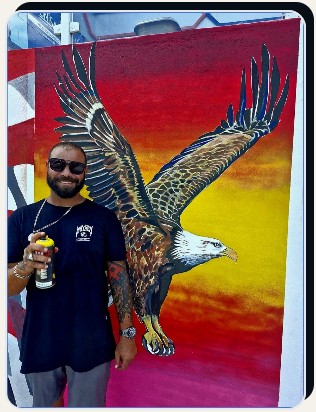 Águia em mural com artista ao lado